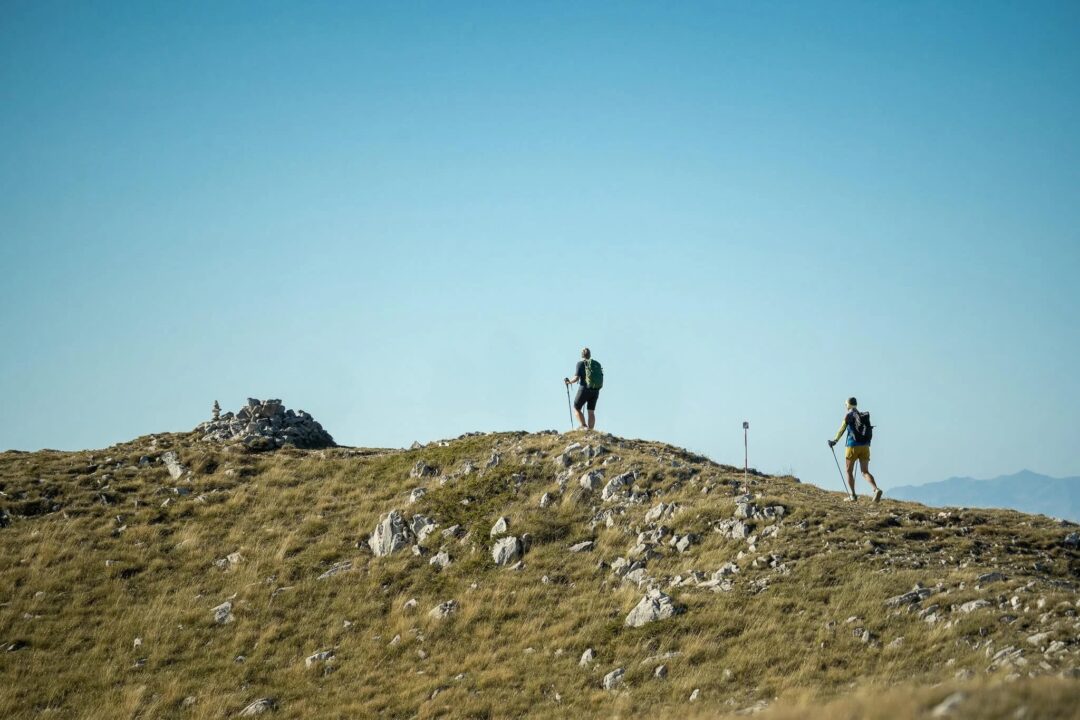 Women hiking on a rocky hilltop under a blue sky