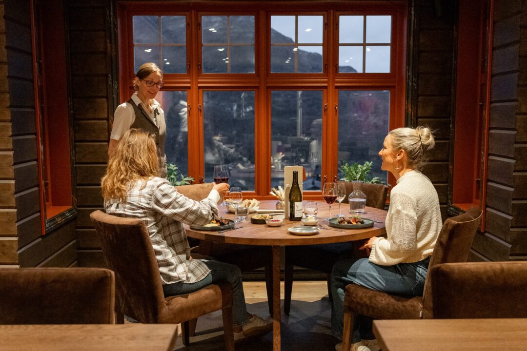 Women dining in a log cabin with views of Jotunheimen National Park mountains