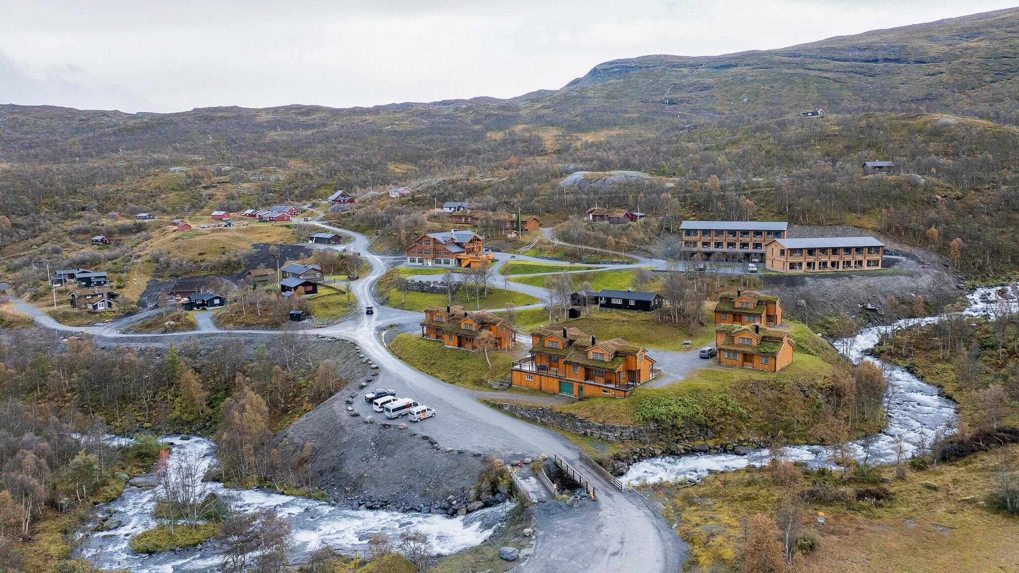 Aerial view of a mountain valley village with a river and winding roads in Norway