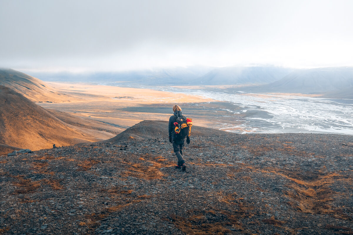 Women hiking along a rocky ridge on an Arctic wilderness expedition near Svalbard with ocean and glaciers in view