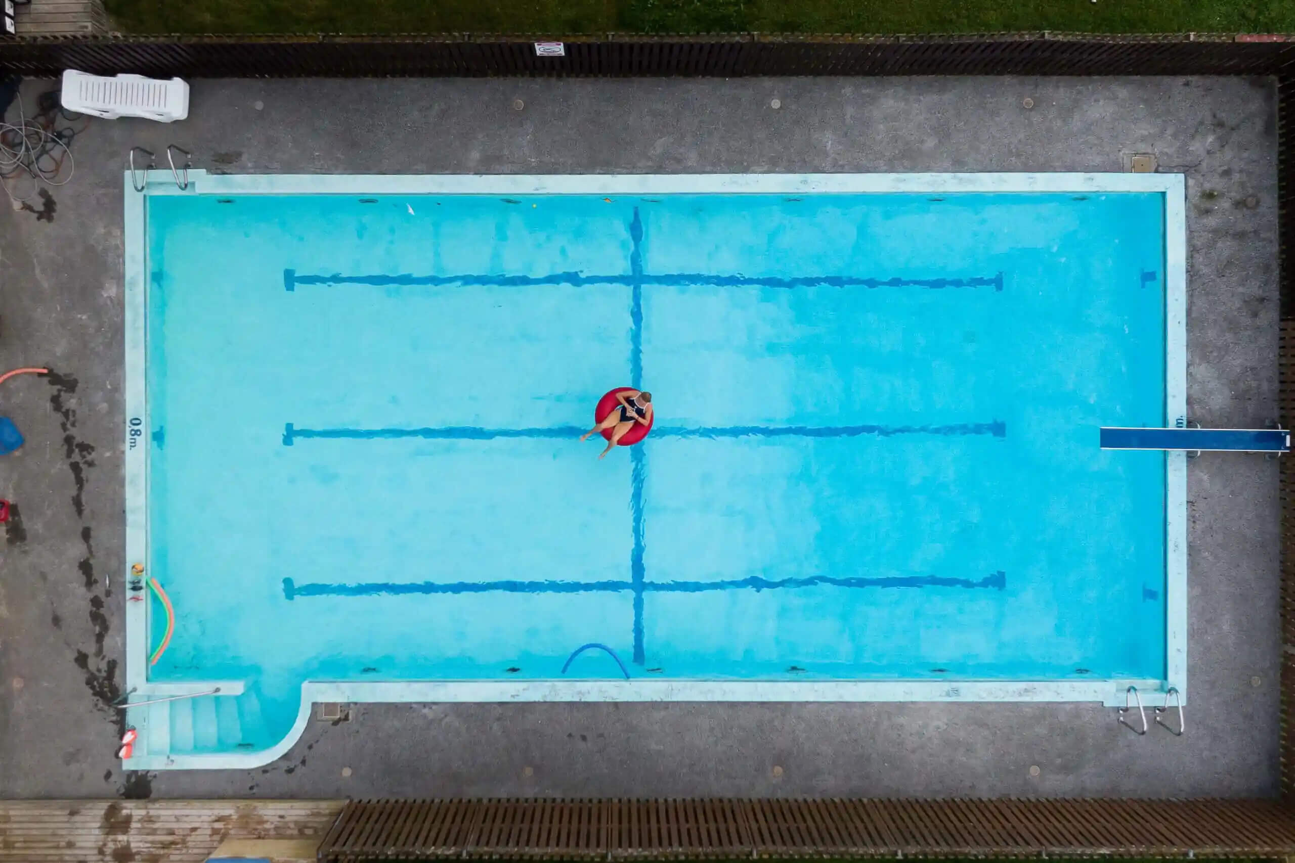 Horse riding arena overhead view with blue surface and jump poles for beginners to practise show jumping