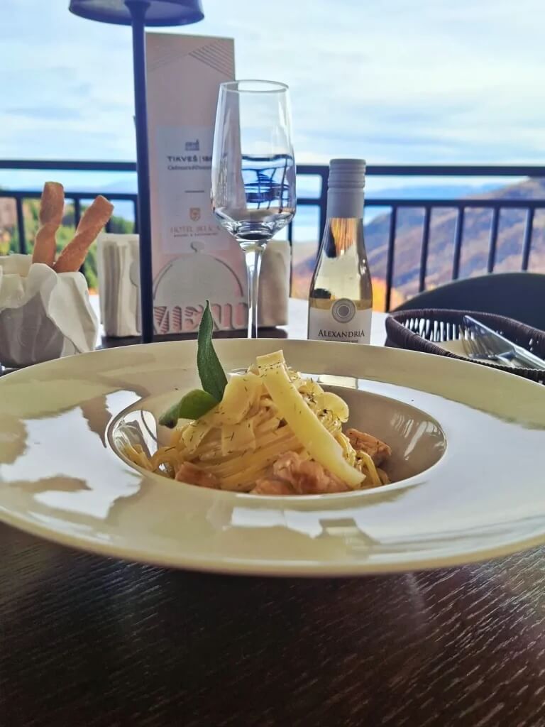 Plate of pasta with wine on a balcony table overlooking Lake view in North Macedonia