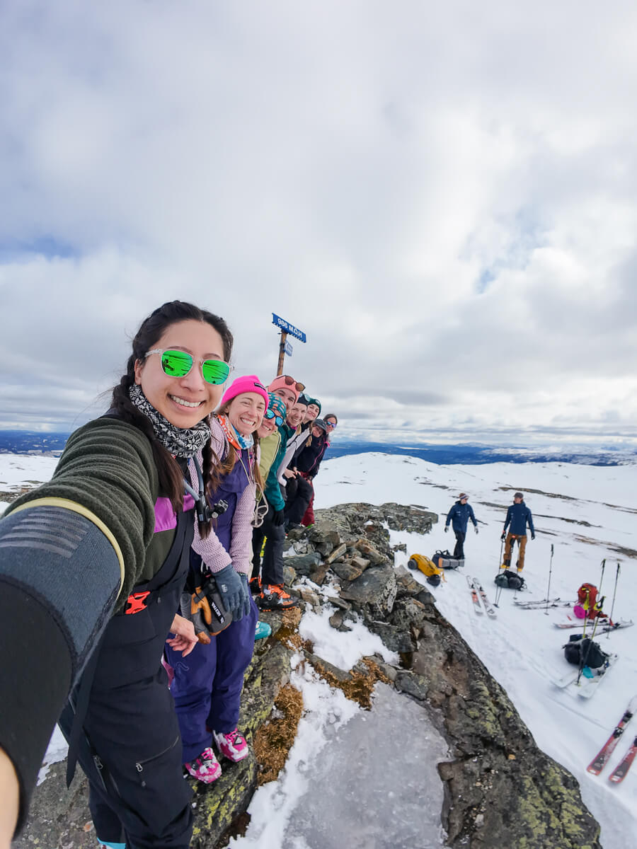 Women ski touring on a snowy ridge under cloudy skies in Sweden, group outdoors with skis and poles