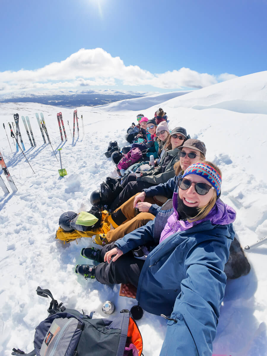 Women ski touring in snowy mountain landscape, grouped on skis on a bright day with mountains in view