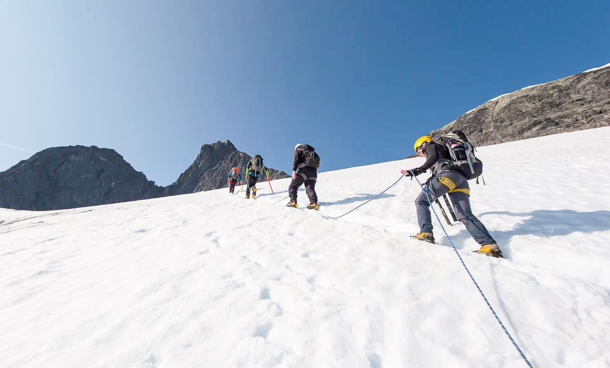 Women skiing on a snowy mountain slope with ski poles and ropes, alpine landscape under a clear blue sky