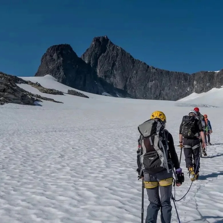 Women hike on a snowy mountain trail with backpacks in Jotunheimen, Norway