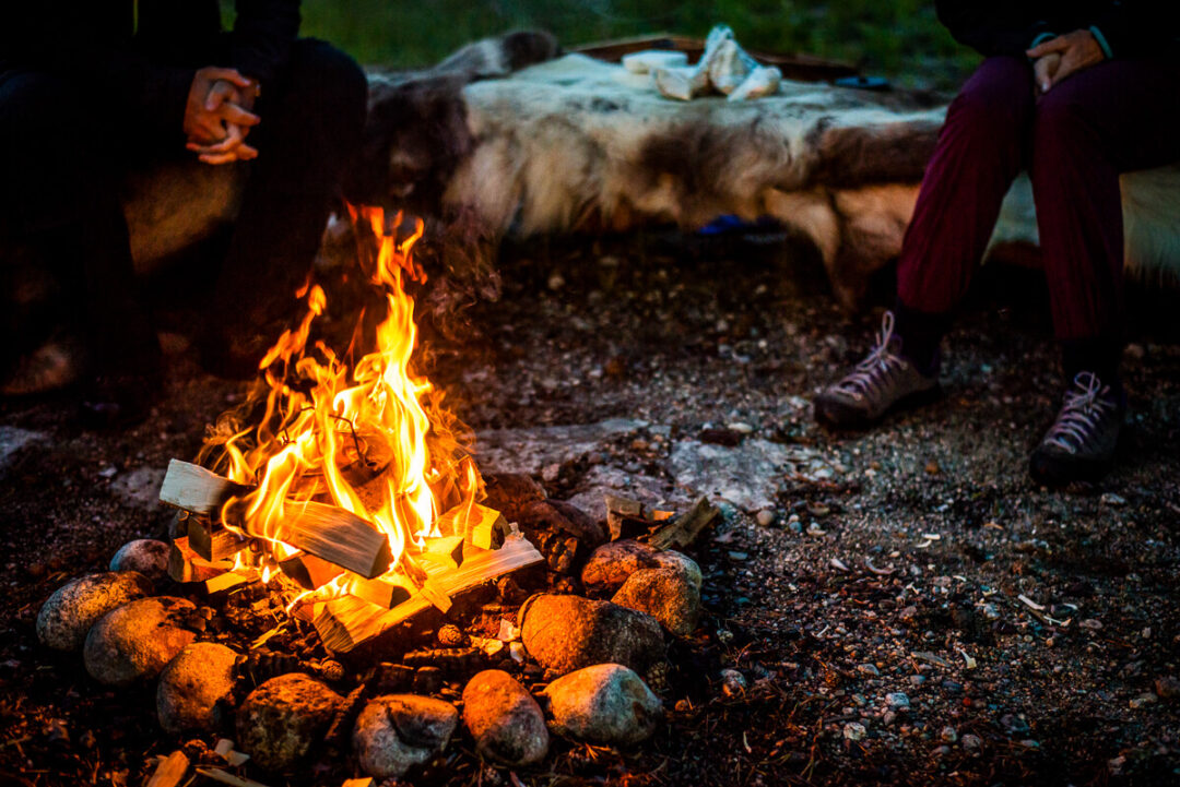 Women camping by a campfire in Swedish Lapland during a multi-activity wilderness adventure