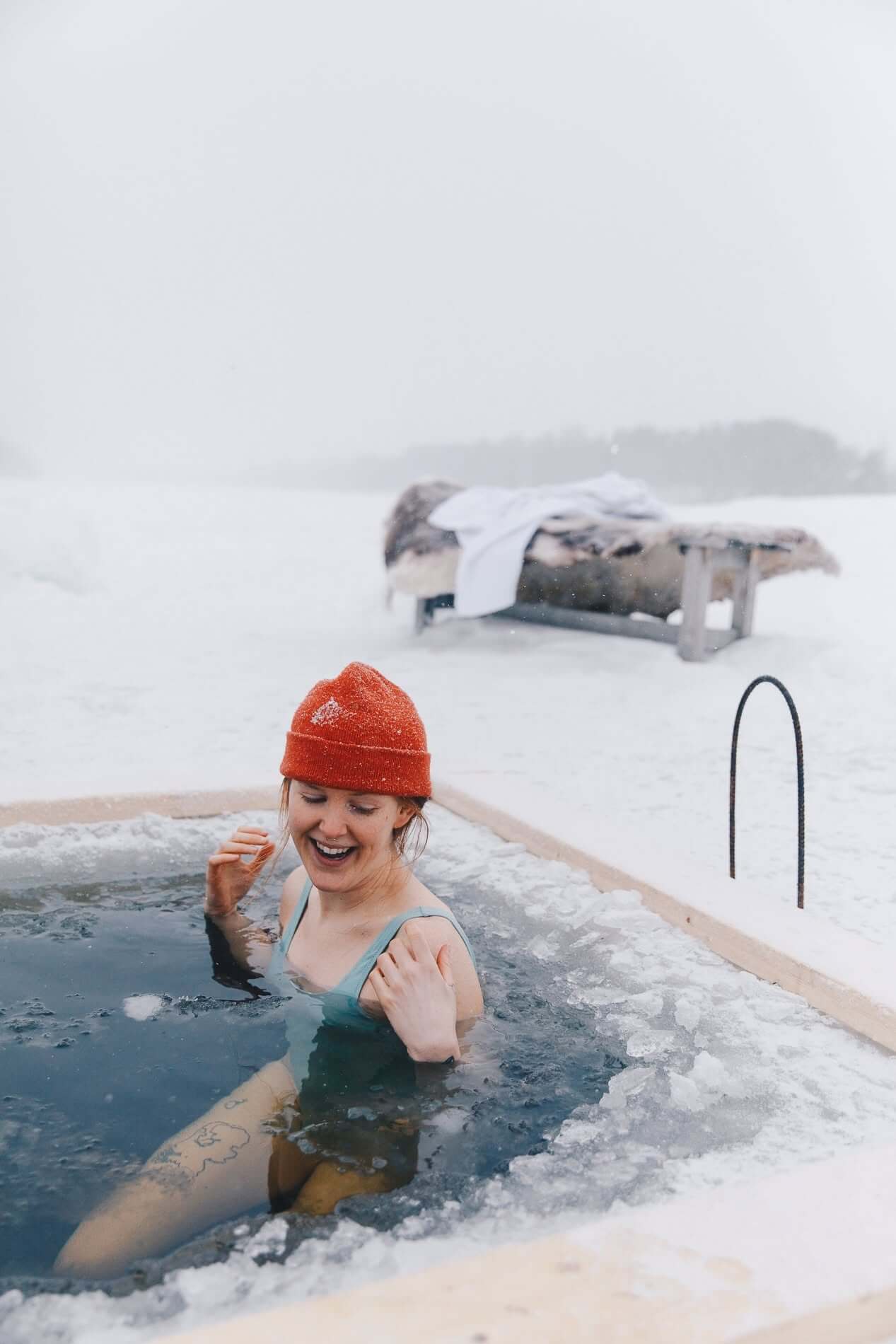 Women in a hot tub in snowy Lapland during winter, smiling in icy outdoor water
