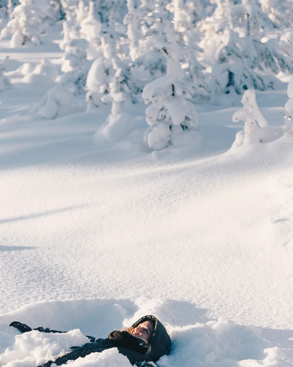 Woman crouched in deep snow in a wintry snowy mountain landscape