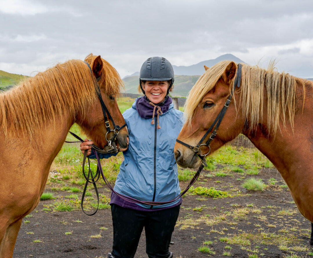 Women leading horses with saddles outdoors in Iceland’s countryside, ready for a beginner horseback riding holiday