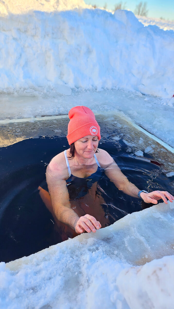 Woman relaxing in an outdoor ice bath with snow and frosted walls in a winter setting