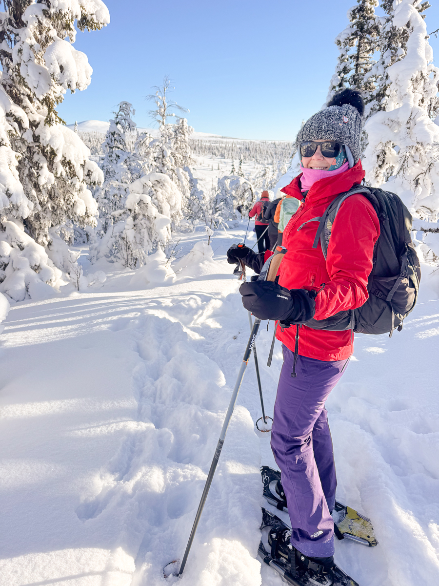 Woman cross-country skiing through snowy Norwegian forest, wearing skis, winter hat and backpack