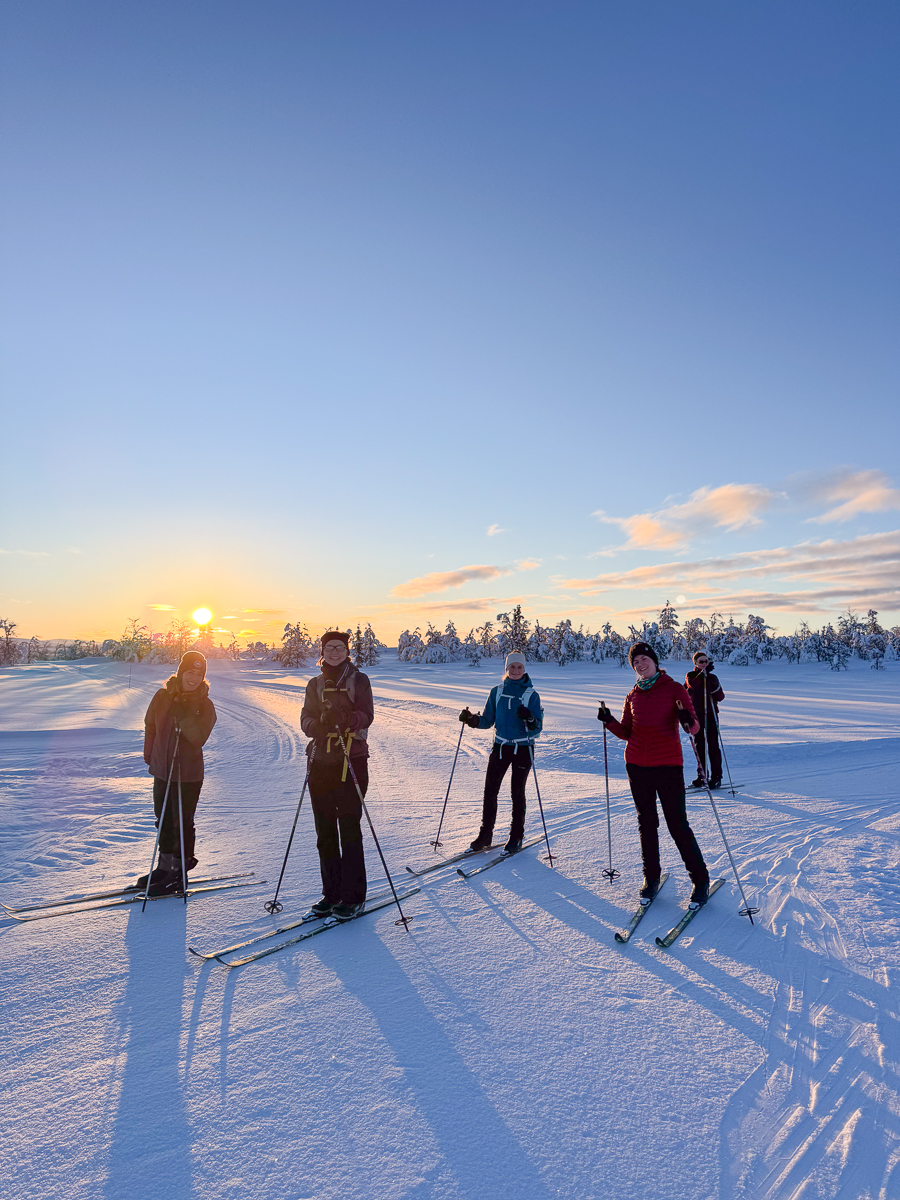 Women cross-country skiers on snowy tracks at sunrise in a winter landscape