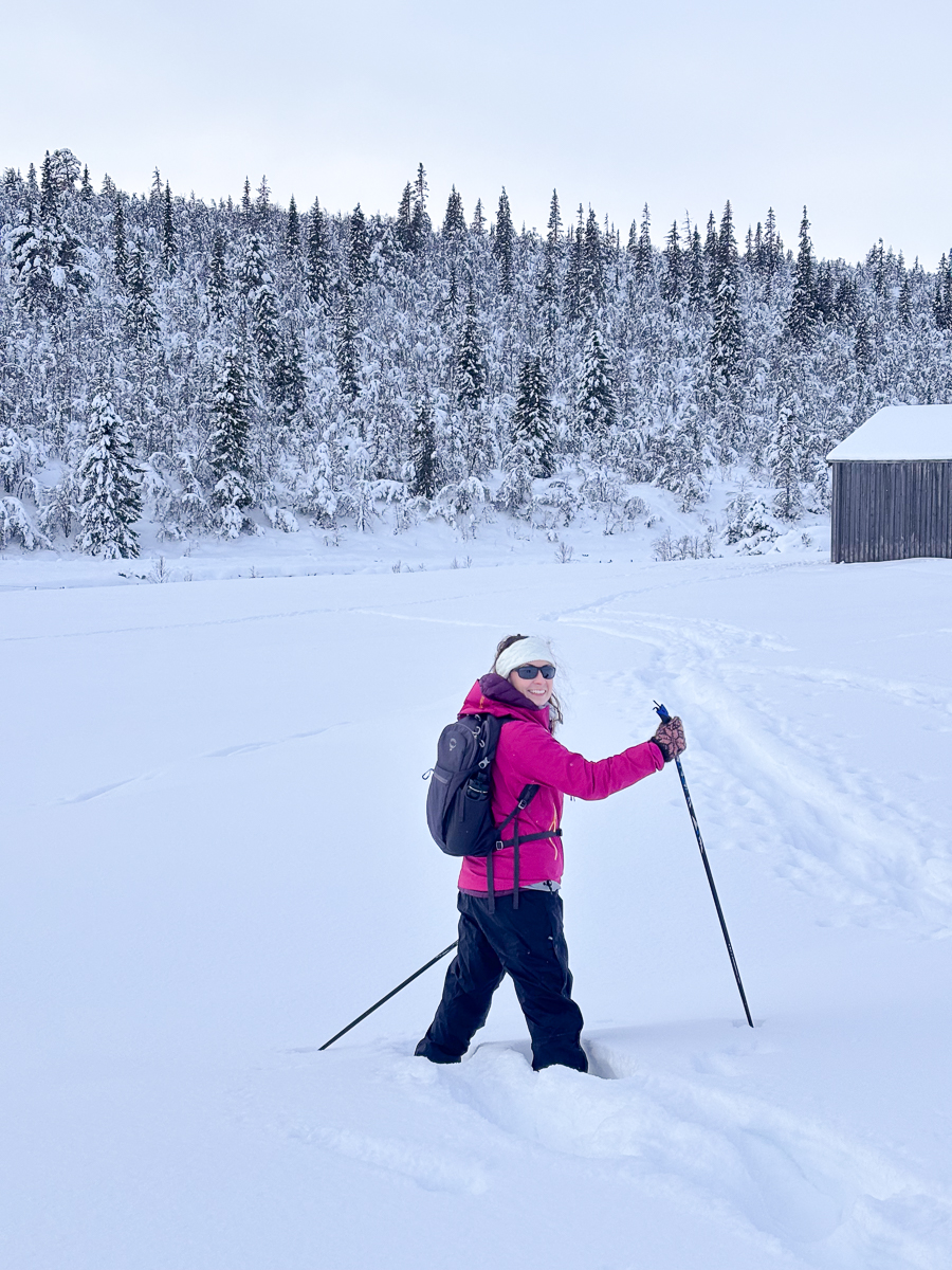 Women cross-country skiing in snowy forest in Norway, winter landscape with backpack and poles.