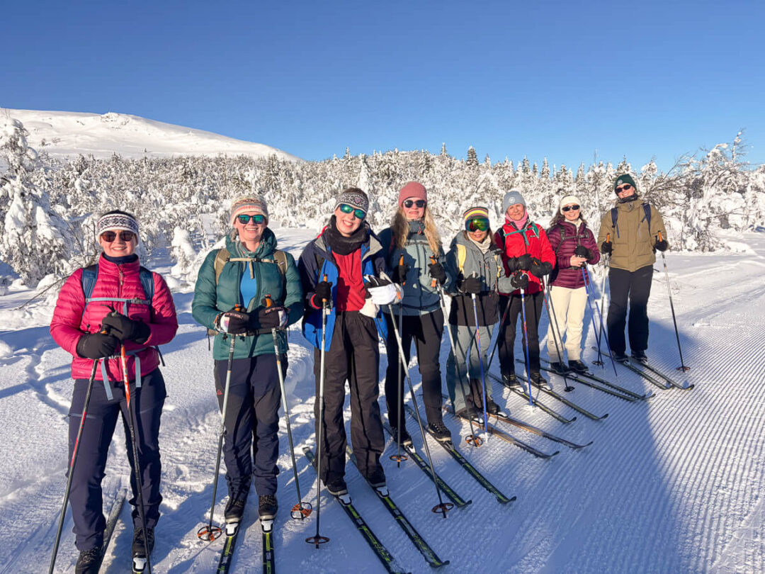 Women cross-country skiing with skis on snowy tracks in Norway, group holiday outdoors in winter mountains