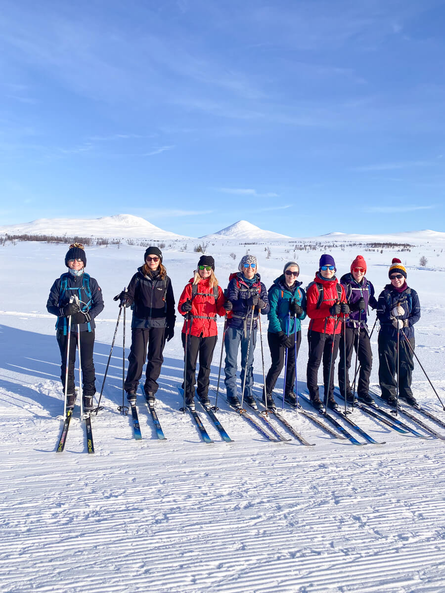 Women cross-country skiing on a snow-covered trail in a mountainous winter landscape