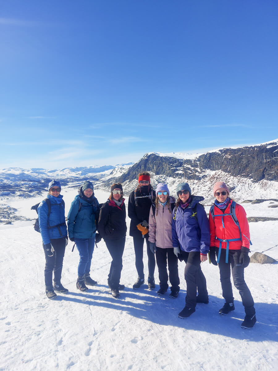 Women in ski gear posing on a snowy mountain slope under a clear blue sky