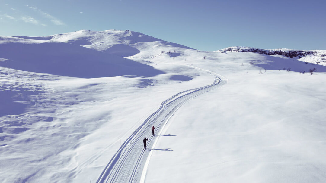 Skiers on a marked ski piste through snowy mountains in Norway