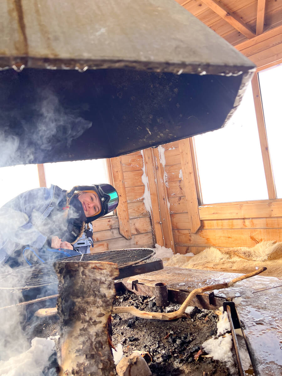 Woman cutting wood with a power tool, sparks and smoke inside a wooden shelter