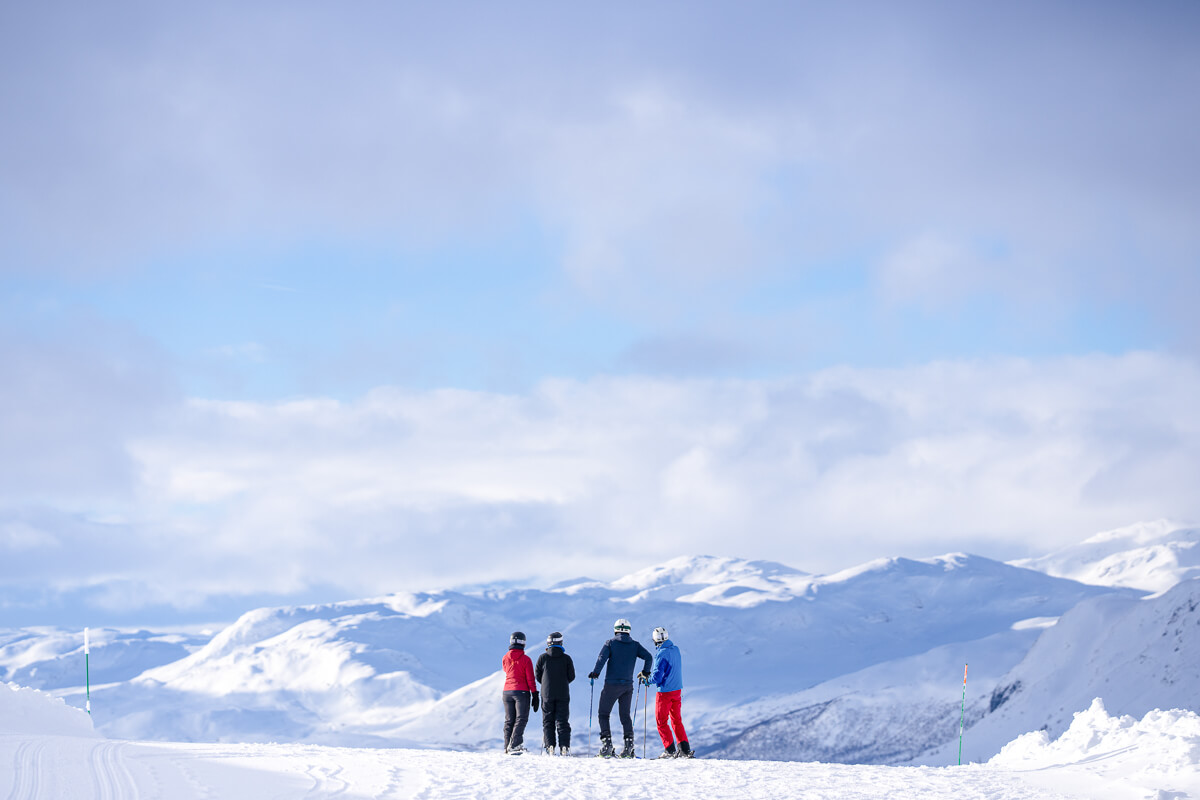 Women skiing on a snowy mountain ridge under a blue sky