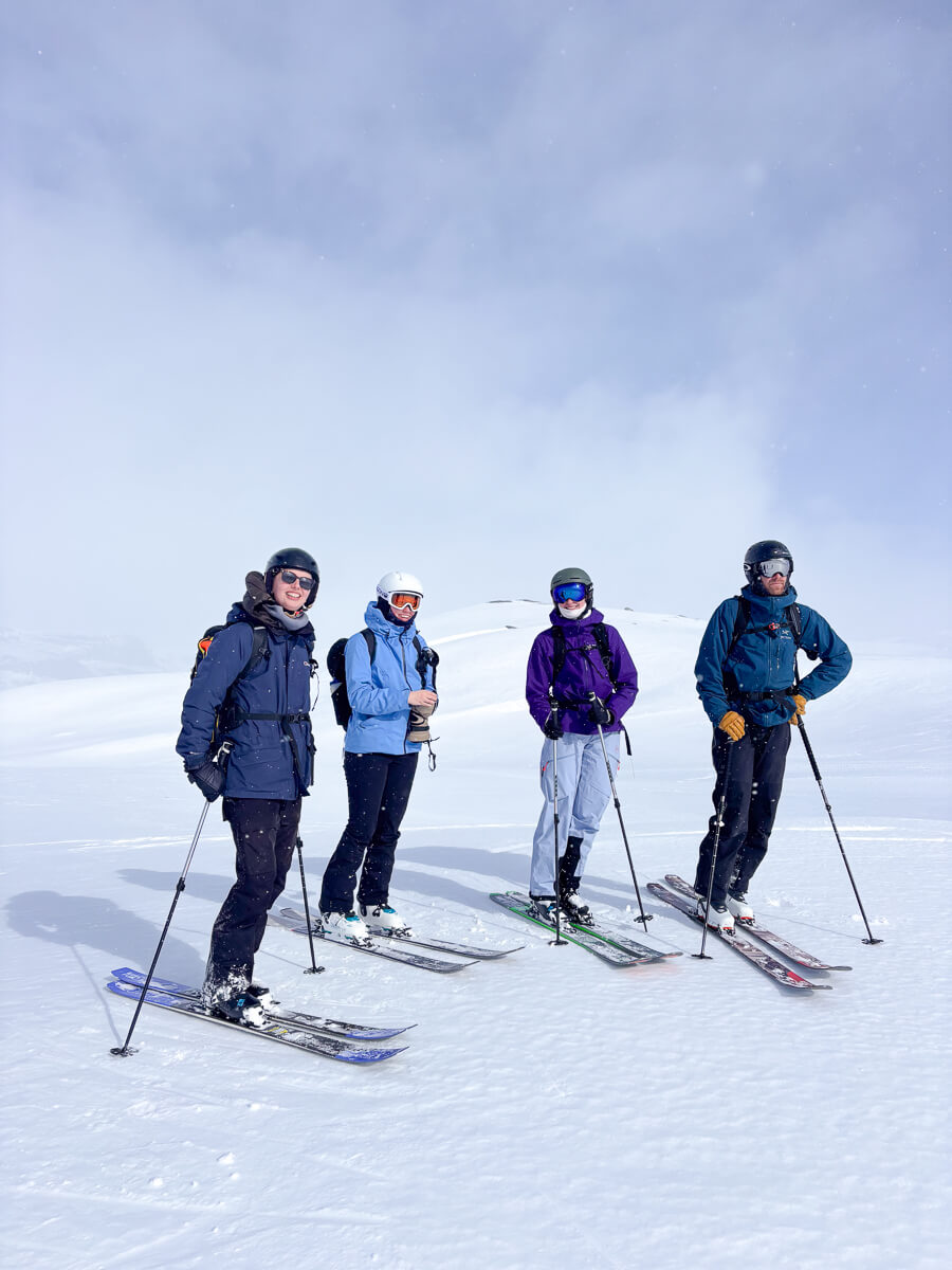 Women ski touring together on snowy mountain slopes with poles, under a clear blue sky