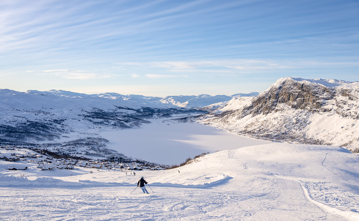 Skier crossing a snow-covered slope with a wide view over a Norwegian winter mountain valley
