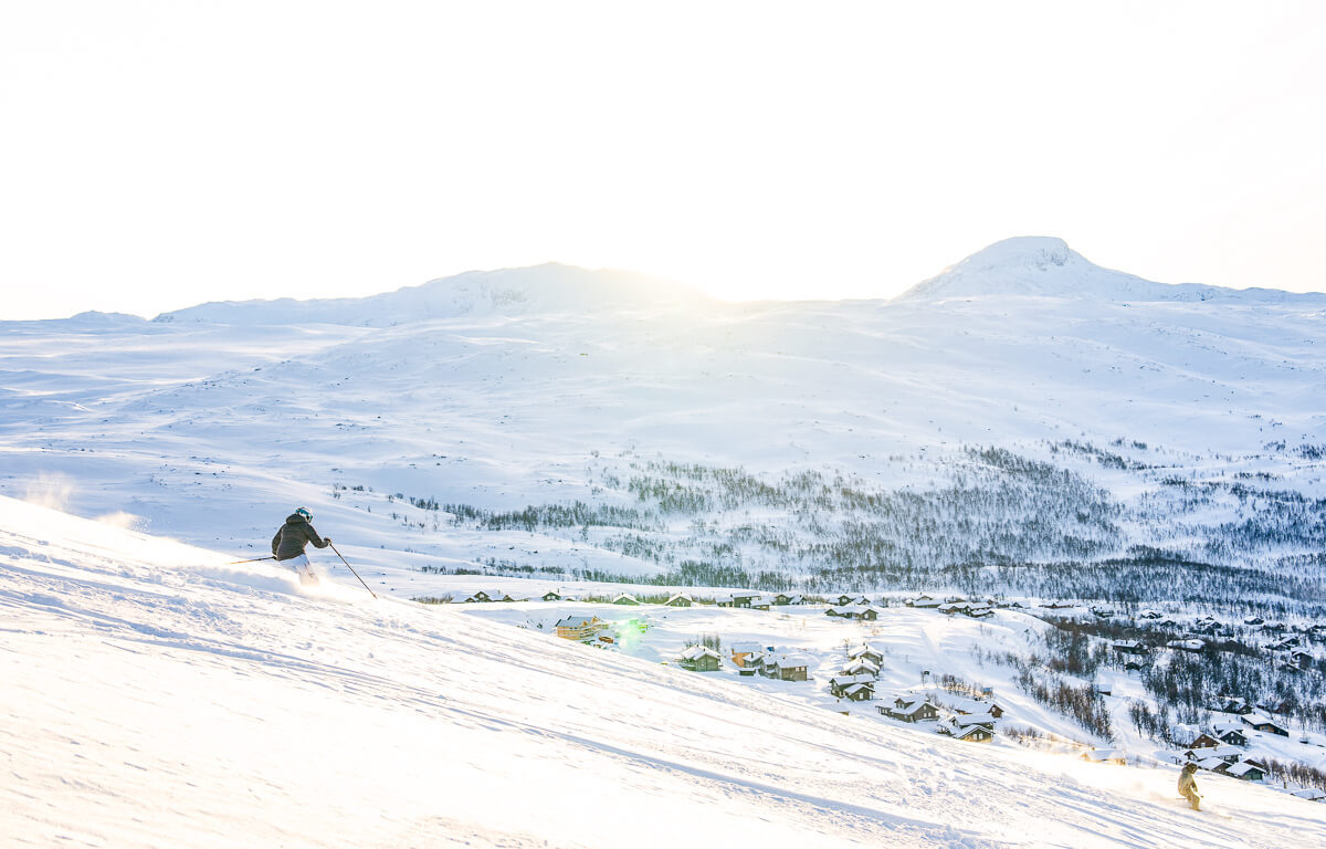 Skier gliding down a snow-covered slope in Norway, overlooking a winter valley village