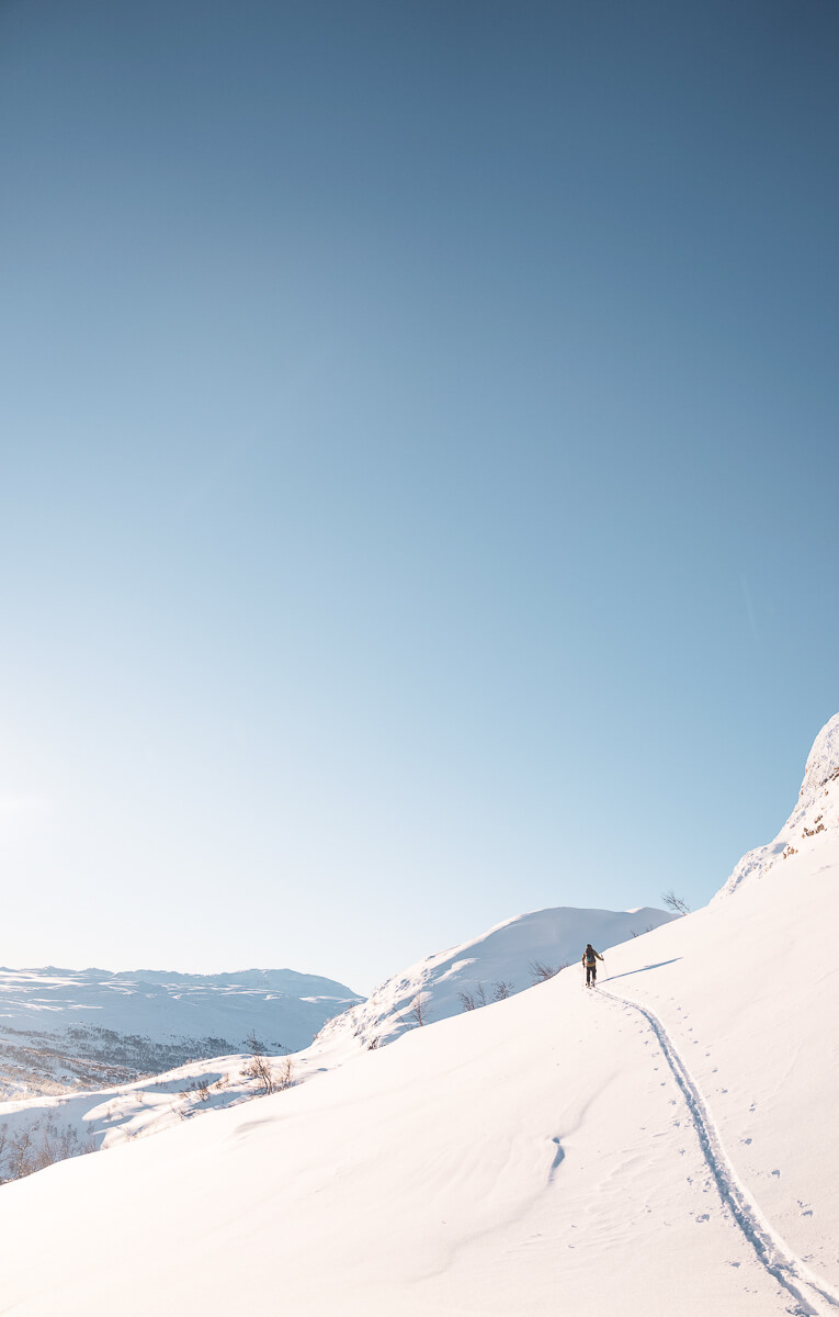Woman ski touring uphill on a snowy mountain ridge in Norway