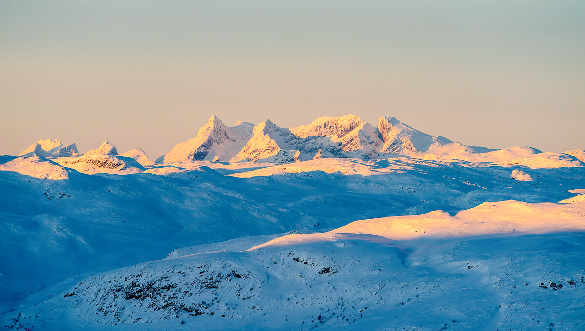 Snow-covered mountain landscape in Norway at sunrise, ideal for ski touring in the Alps-like terrain.