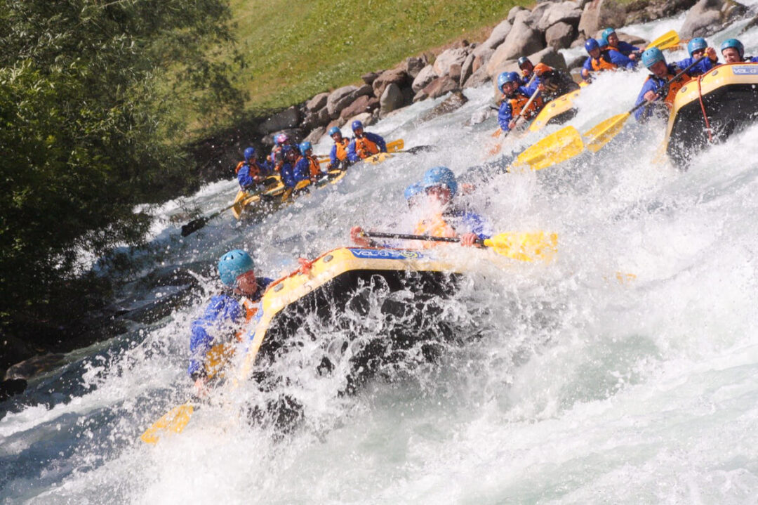 White-water rafting group on inflatable rafts, splashing through fast rapids on a mountain river