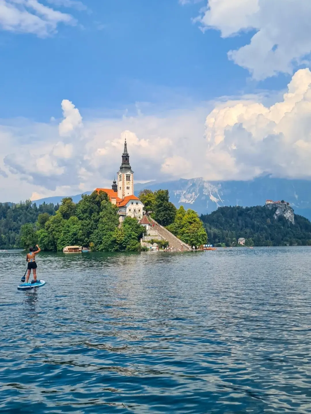 Woman paddleboarding on a lake near a church island in Slovenia
