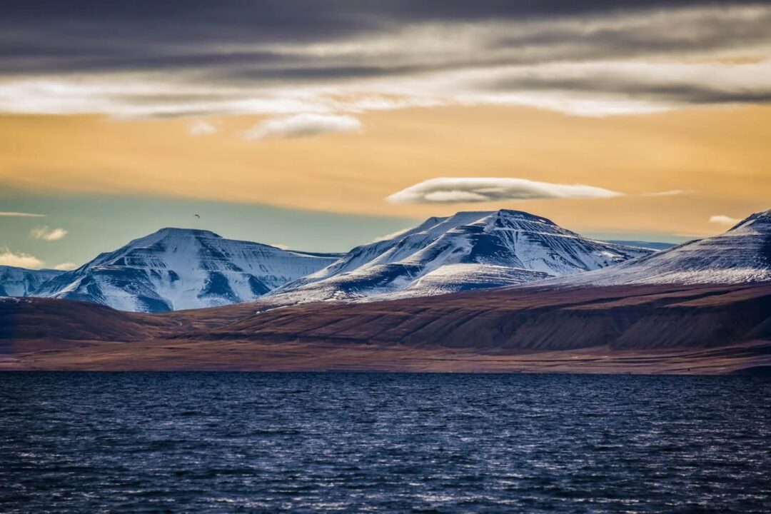Snowy Svalbard mountains and fjord at sunset for an Arctic wilderness summer expedition
