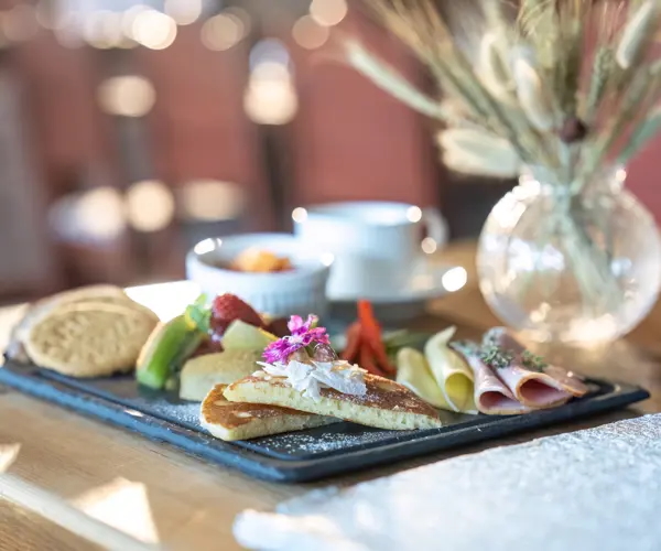 Breakfast open sandwiches and salad on a serving tray, with cups and bread in the background
