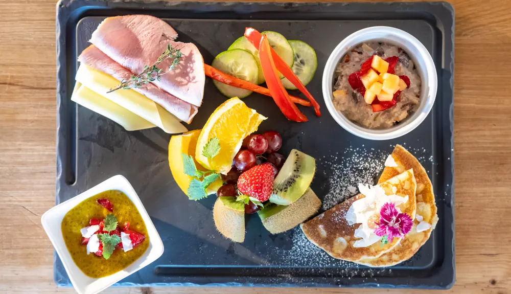 Meal tray with sandwiches, fruit and vegetables, plus dips and flatbread on a table.