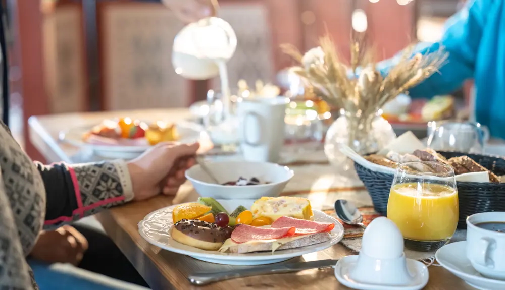 Breakfast table with plates, pastries and juice, served to seated women indoors