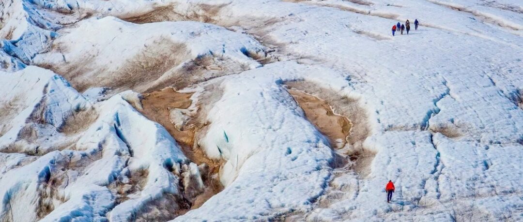 Hikers on a snow-covered glacier in Arctic wilderness, Svalbard summer expedition trail