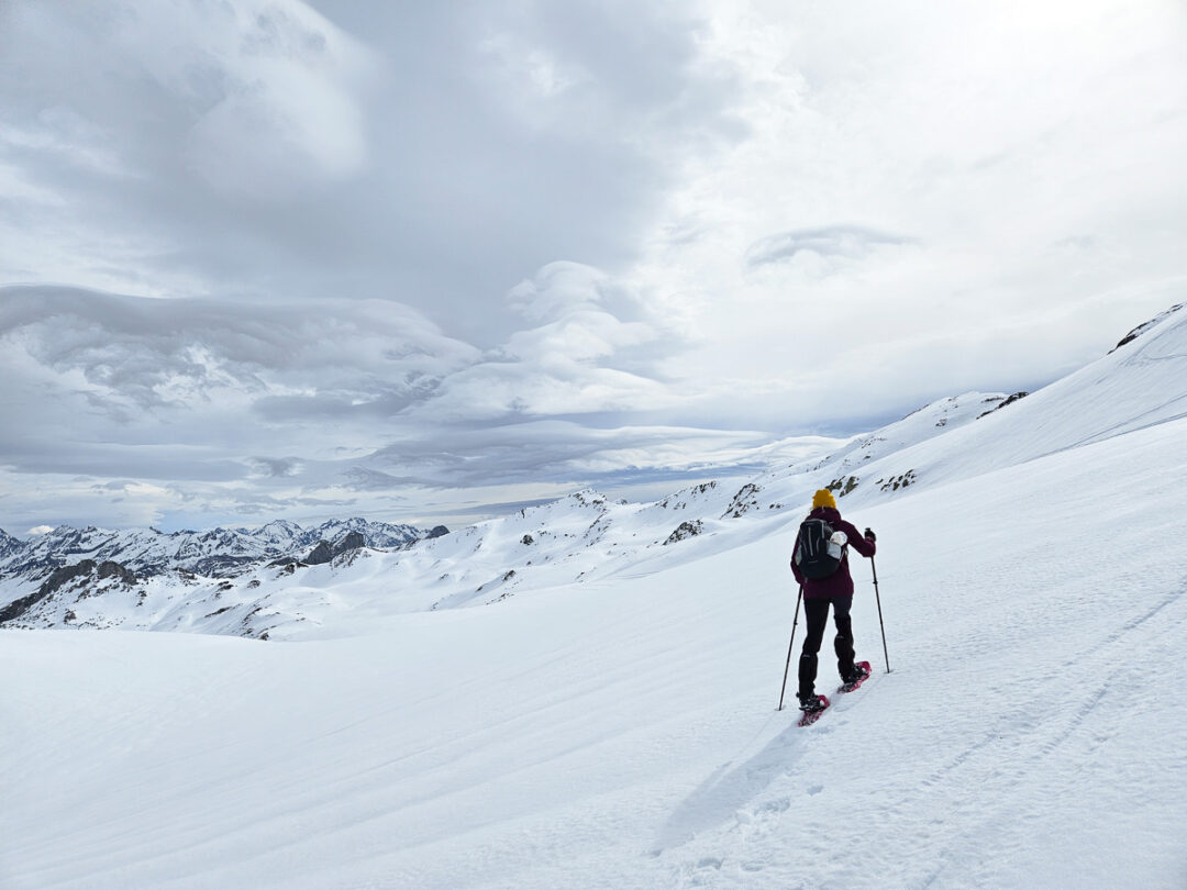 Woman skiing across a snowy mountain slope under cloudy skies