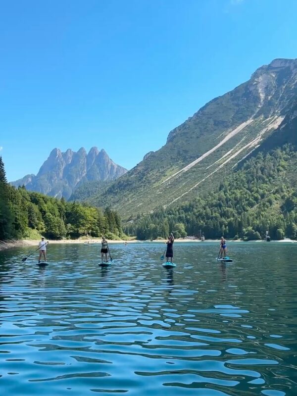 Women paddleboarding on a calm lake in Slovenia with mountain peaks in the background