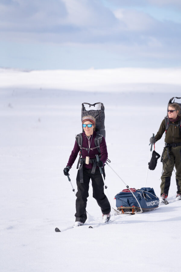 Women backcountry skiing with skis and poles on a snowy mountain slope in winter conditions
