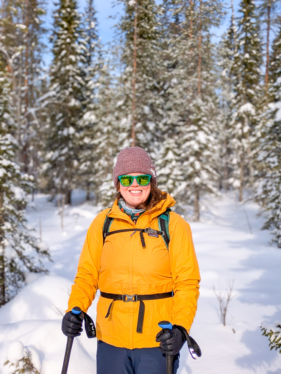 Woman skiing in a snowy forest, wearing bright jacket, goggles and skis in winter landscape