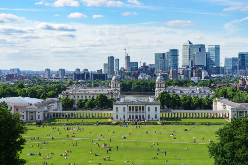 Panoramic view of London skyline over manicured park lawns under a blue sky