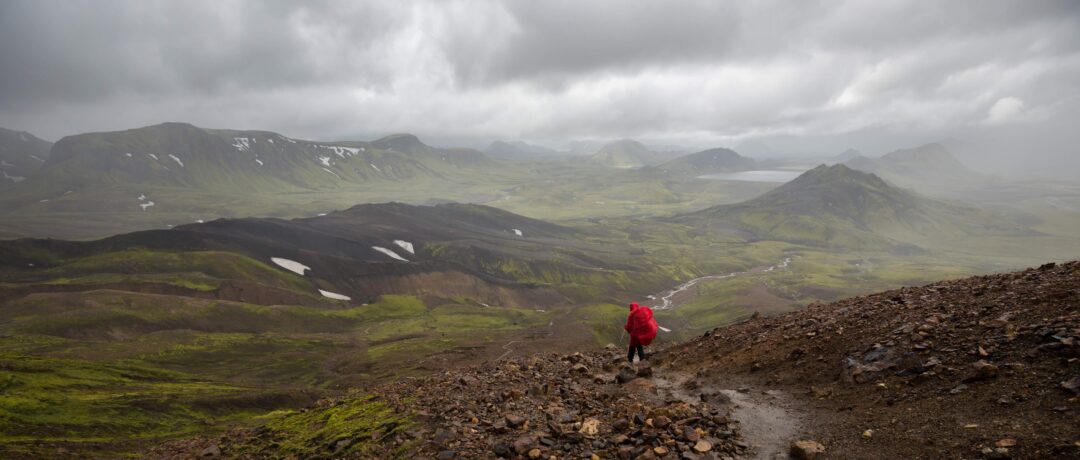 Woman hiking on a misty mountain trail through rocky terrain in the UK countryside during bad weather