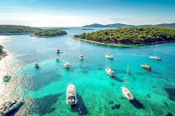 Aerial view of sailing boats over turquoise Adriatic sea near Croatia’s coastline and islands.