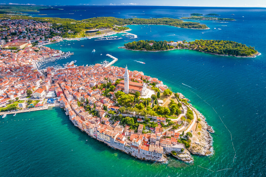 Aerial view of a coastal town and harbour with breakwater, surrounded by blue sea