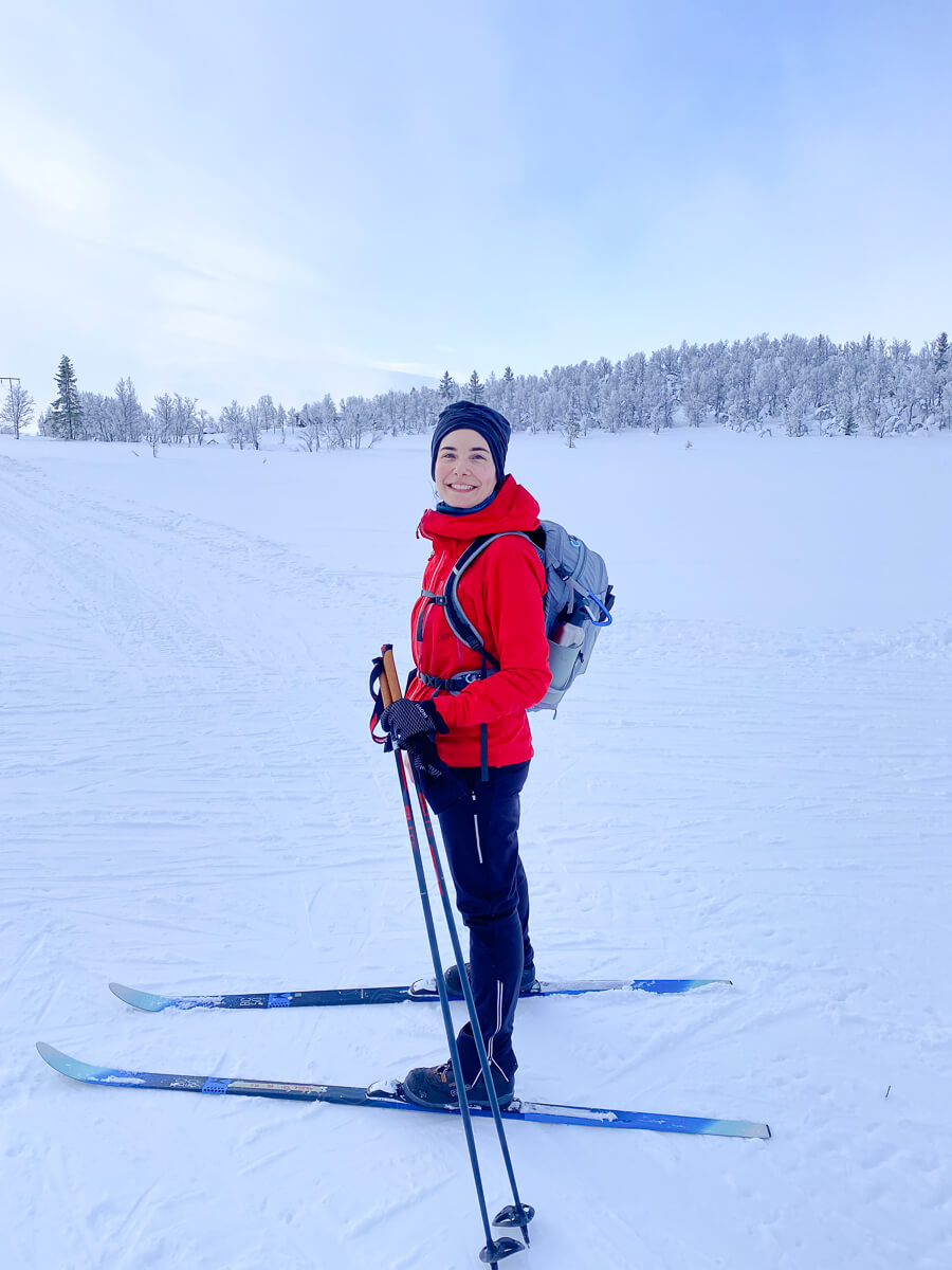 Smiling woman cross country skier in snowy landscape.