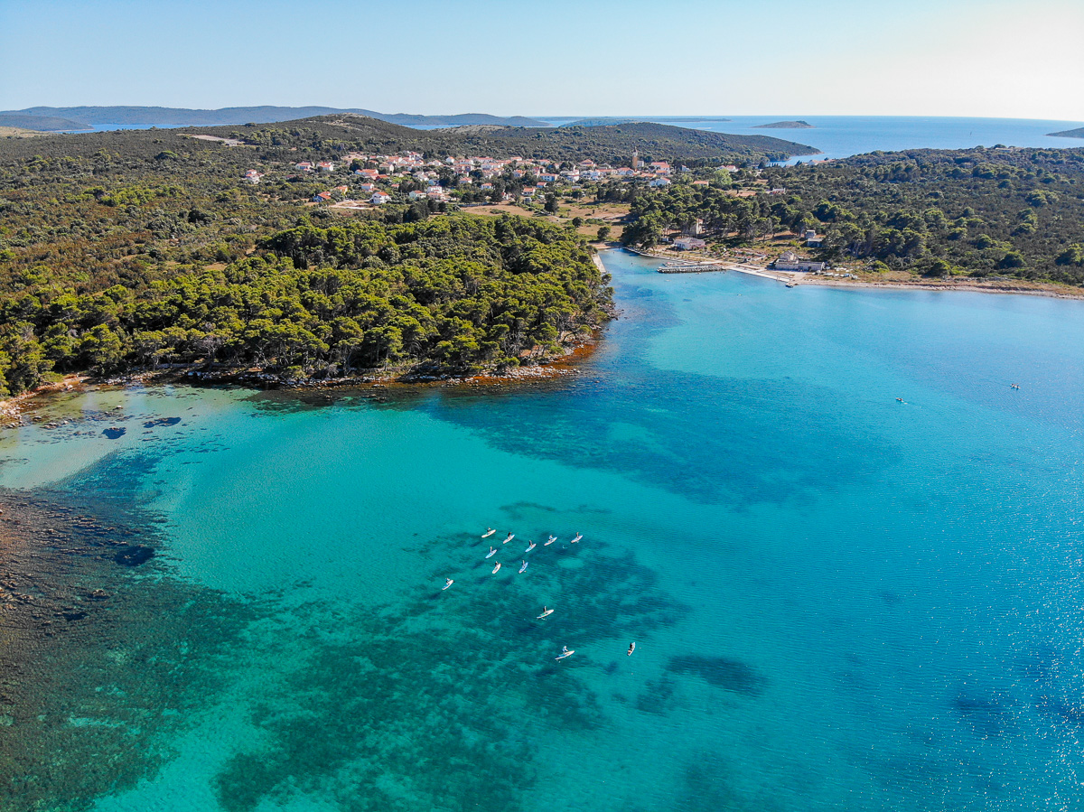 Aerial view of a turquoise coastal bay with swimmers off the shoreline