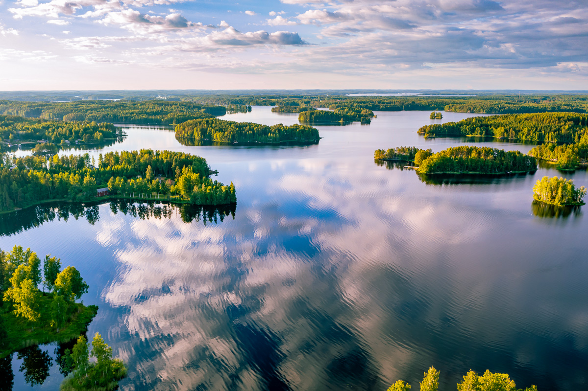 Aerial view of a calm river winding through forest and islands under a cloudy sky in Europe