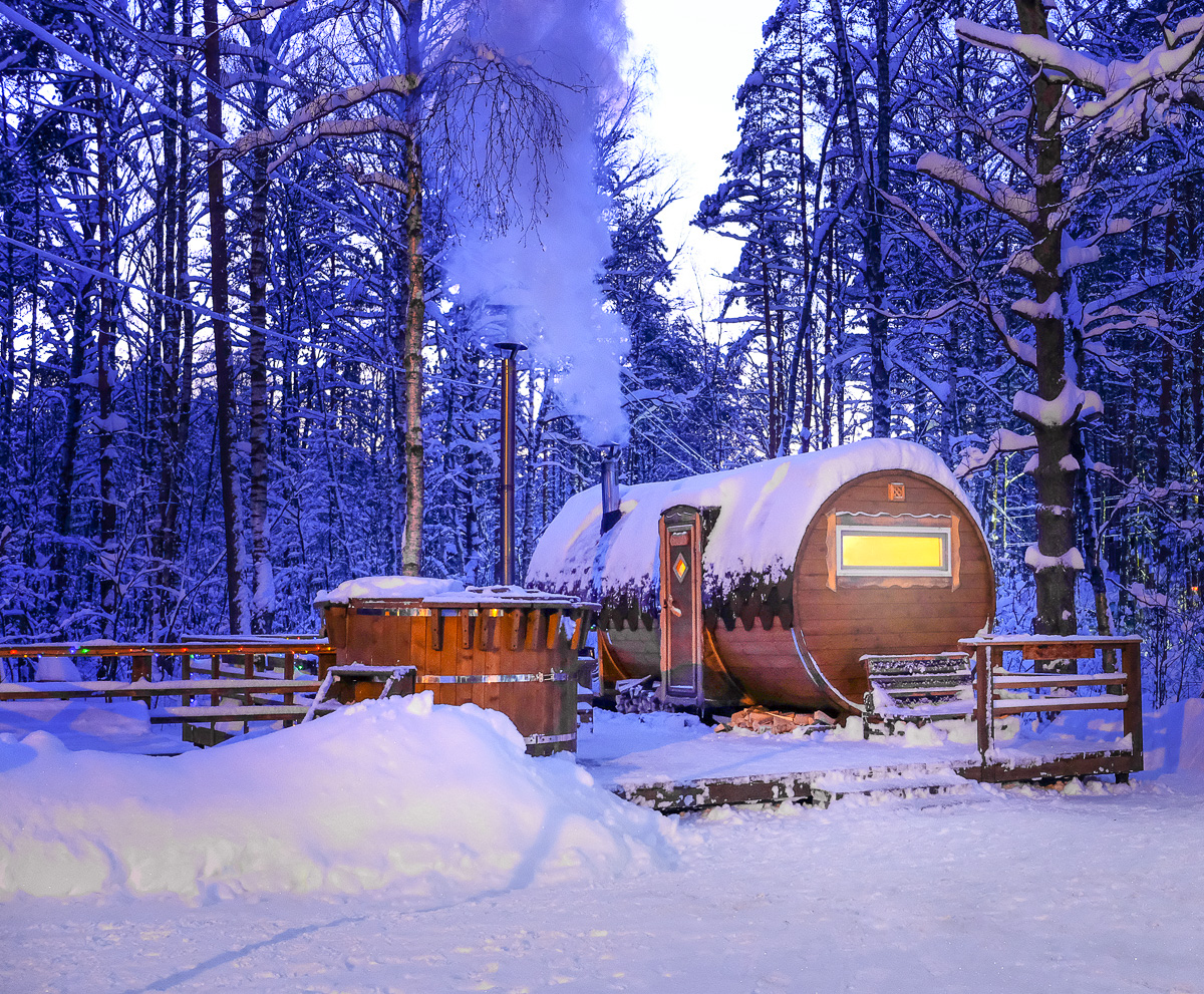 Wooden winter camping cabin in a snowy forest with trees covered in snow and misty light