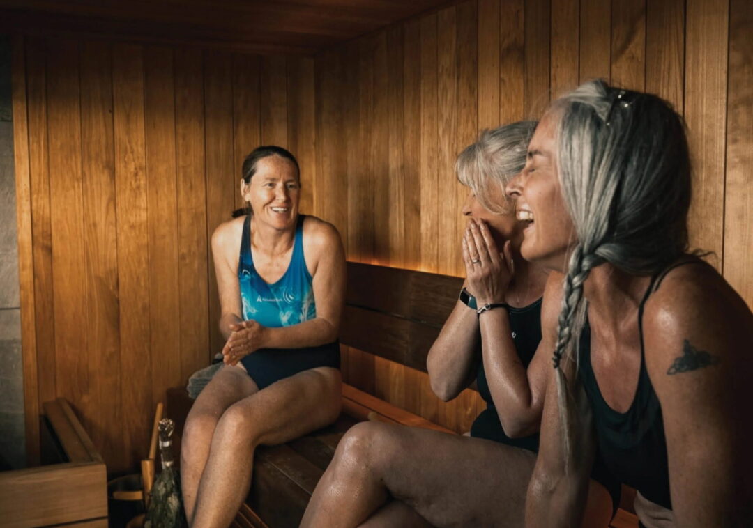 Women relaxing and laughing in a wooden sauna interior