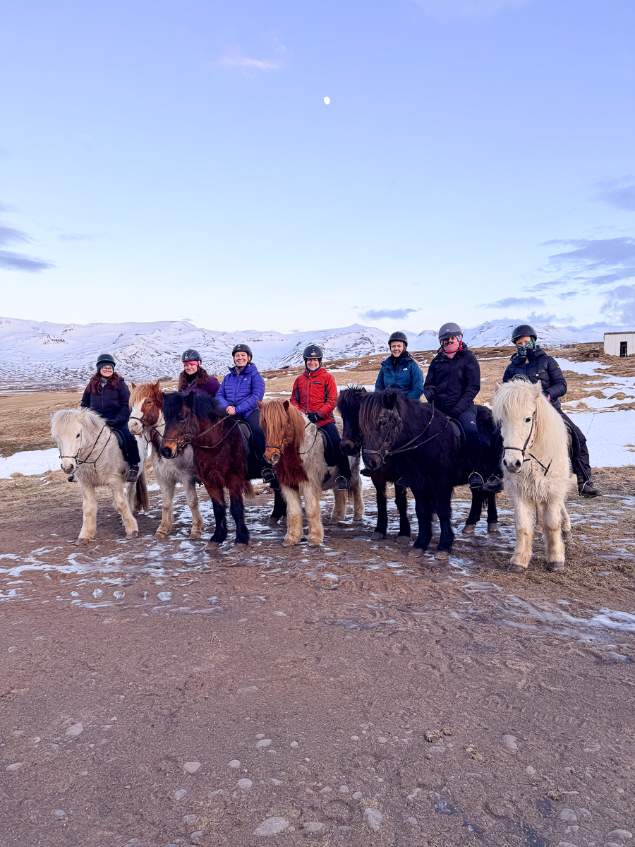 Women on horseback posing during a winter ride in a snowy mountain landscape
